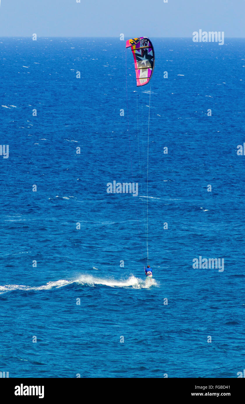 Un uomo di Kitesurf in cristallo baie di Cipro. Un sport acquatici per cui un kite surfer controlla una potenza kite e cavalca le onde su una w Foto Stock