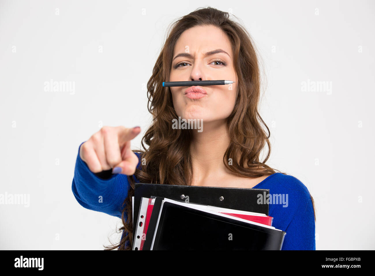 Funny giovane donna con cartelle simitating baffi con penna e puntando  sulla fotocamera su sfondo bianco Foto stock - Alamy
