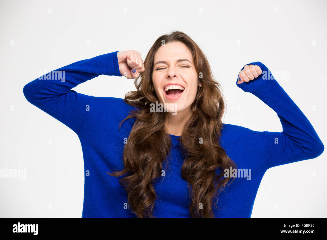 Estatica successo eccitato giovane donna con le mani alzate per celebrare la vittoria su sfondo bianco Foto Stock