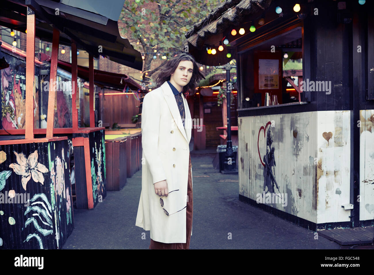 Uomo in piedi in una strada in Shoreditch con un mantello bianco Foto Stock