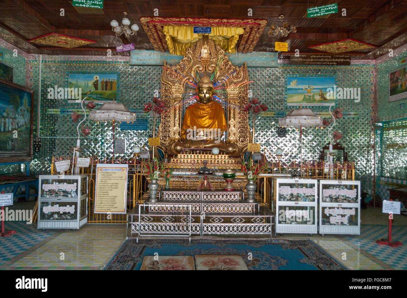 Statua di Budda affiancato da scatole per le donazioni di denaro in una sala di preghiera del presto Oo Ponya Shin Pagoda, Sagaing, Myanmar. Foto Stock