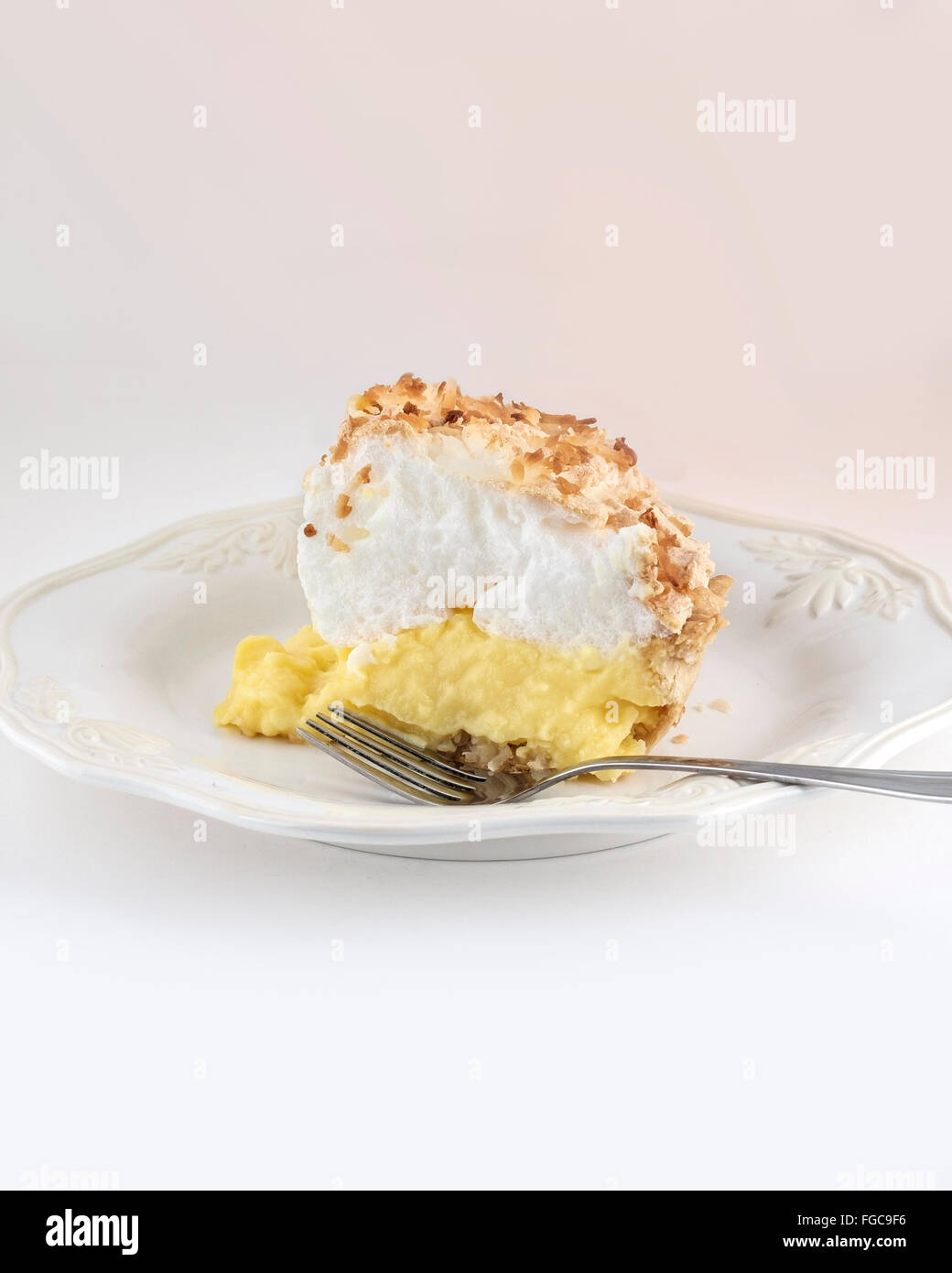 Una fetta di fatti in casa pane appena sfornato cocco torta di meringa isolato su bianco.Colore dissolvenza aggiunto. Foto Stock