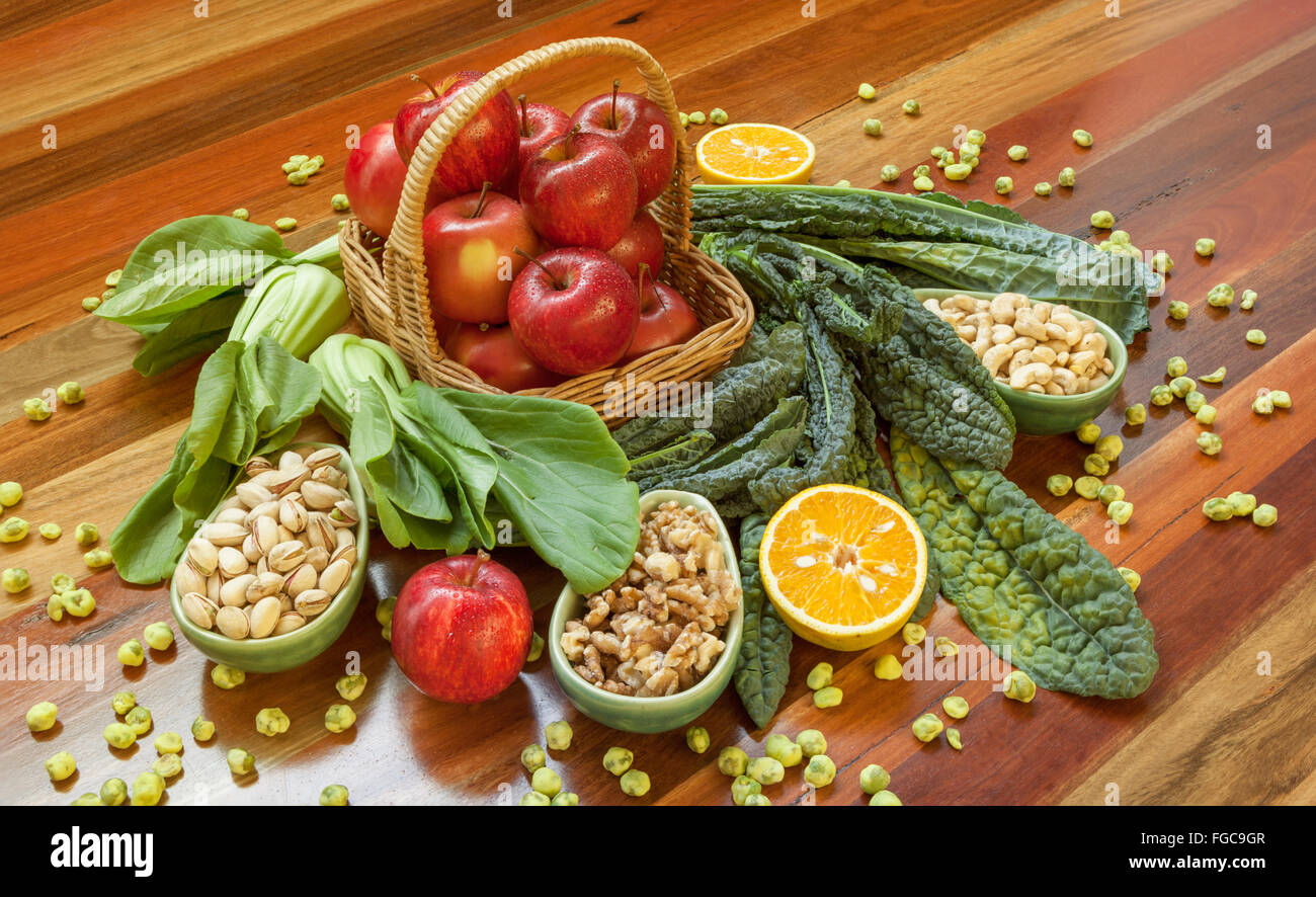 Salute composizione alimentare con le mele nel cestello, verde di foglie e i dadi collocato su un tavolo di legno. Foto Stock