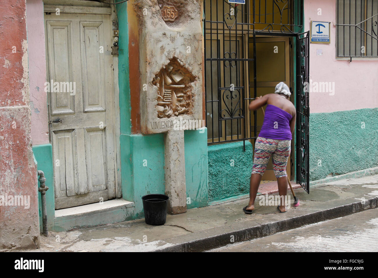 Donna pulizia marciapiede davanti casa Habana Vieja (l'Avana Vecchia), Cuba Foto Stock