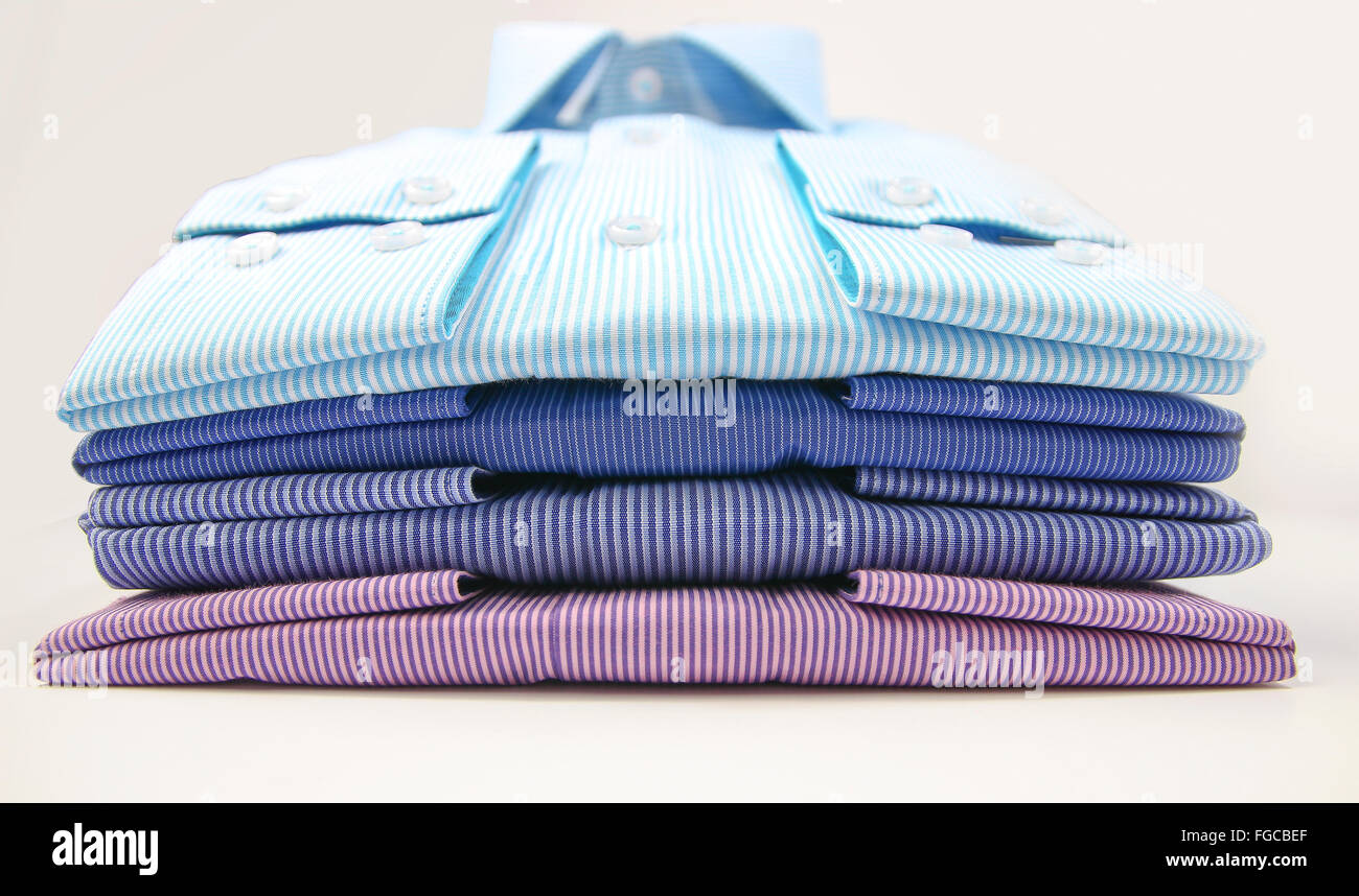 Alcuni colorati magliette uomo ripiegato su sfondo bianco Foto Stock