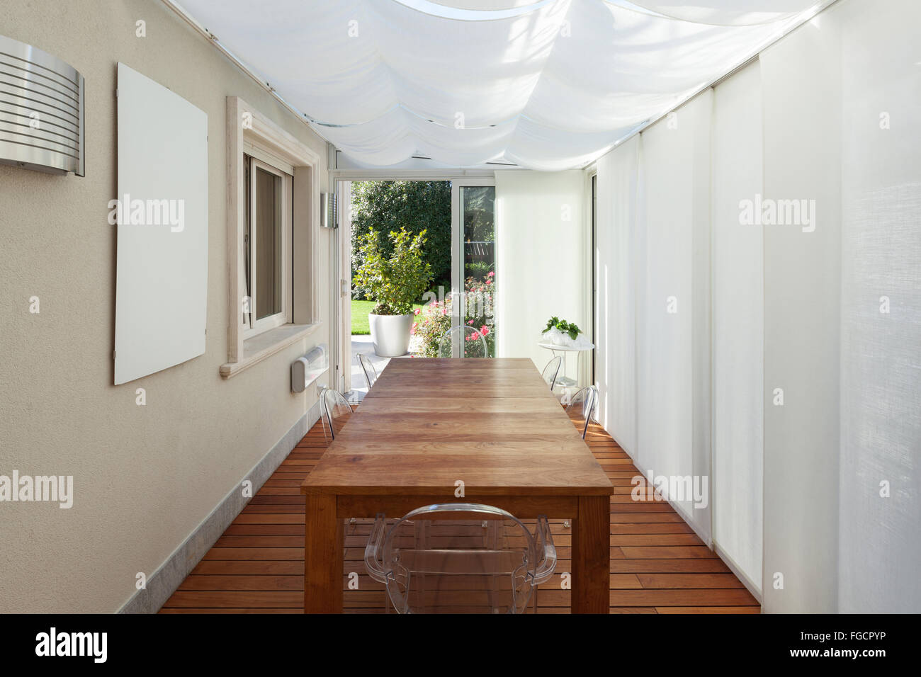 Architettura; veranda con tende bianche e tavolo in legno Foto Stock