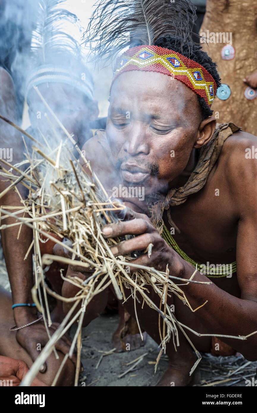 Kalahari San uomo soffiando cannucce per fare fuoco in modo tradizionale. Foto Stock