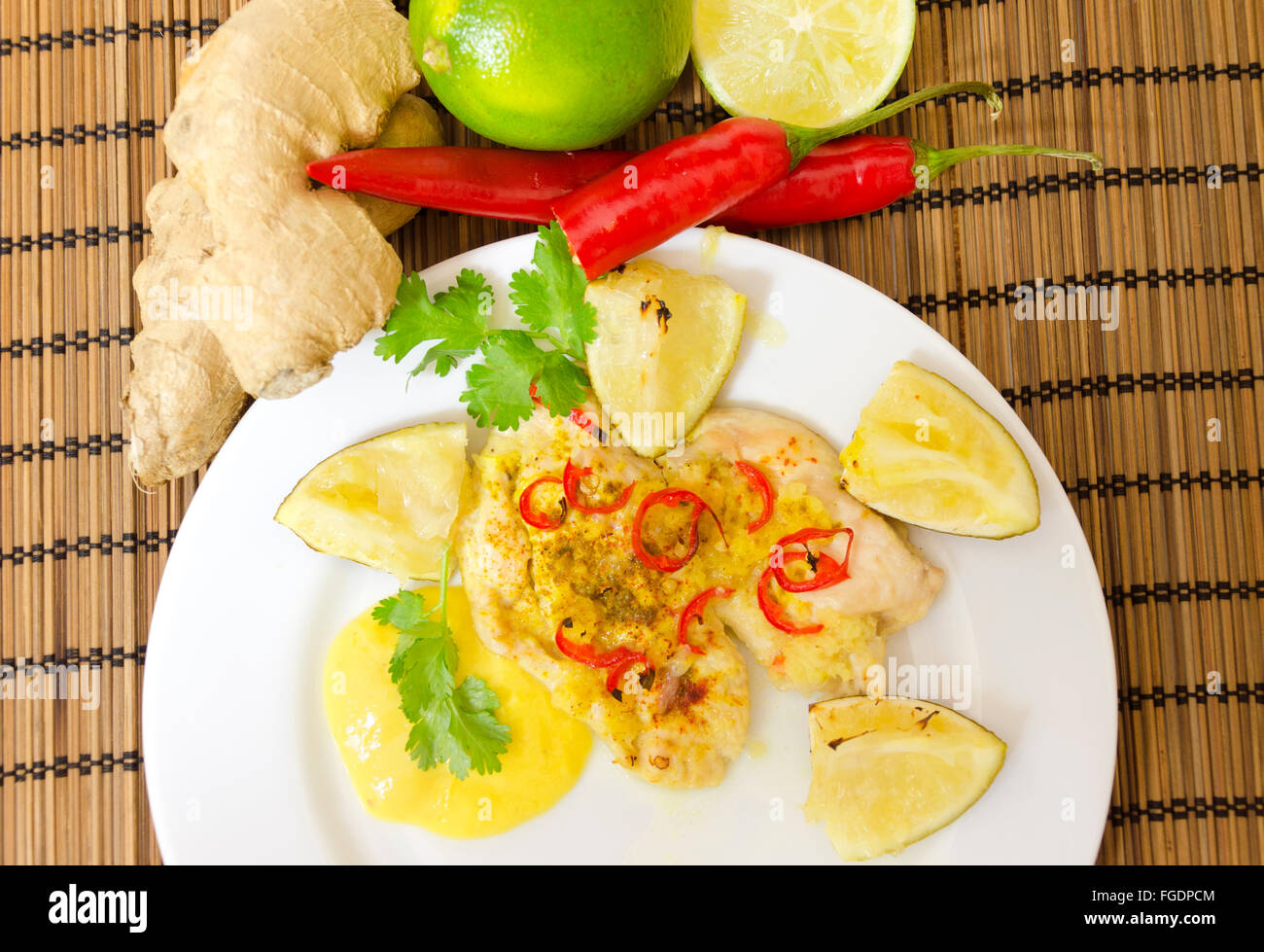 Vista dall'alto di un tostate in forno filetto di pollo guarnito con peperoncino, Zenzero, noce di cocco e la calce e servita in una piastra bianca con uomo Foto Stock