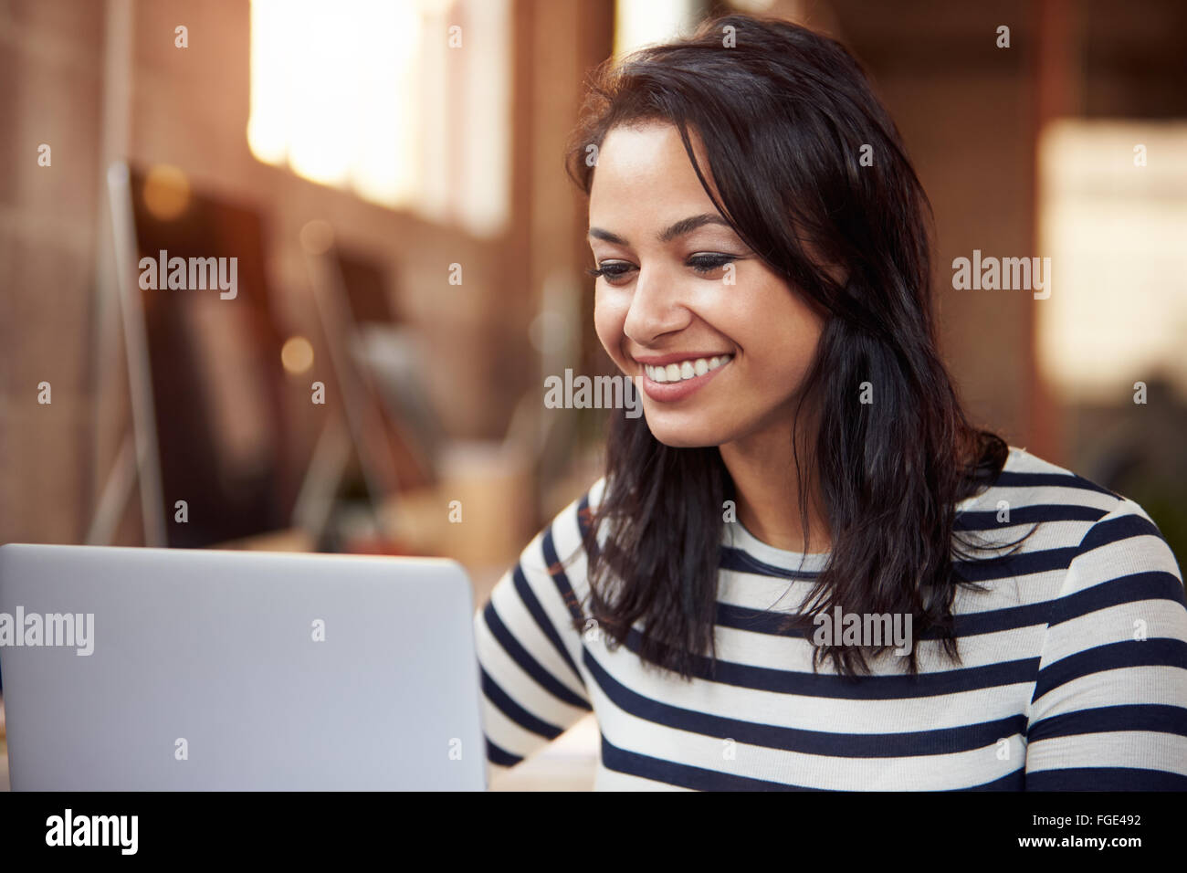 Designer femmina utilizzando laptop alla scrivania in ufficio moderno Foto Stock