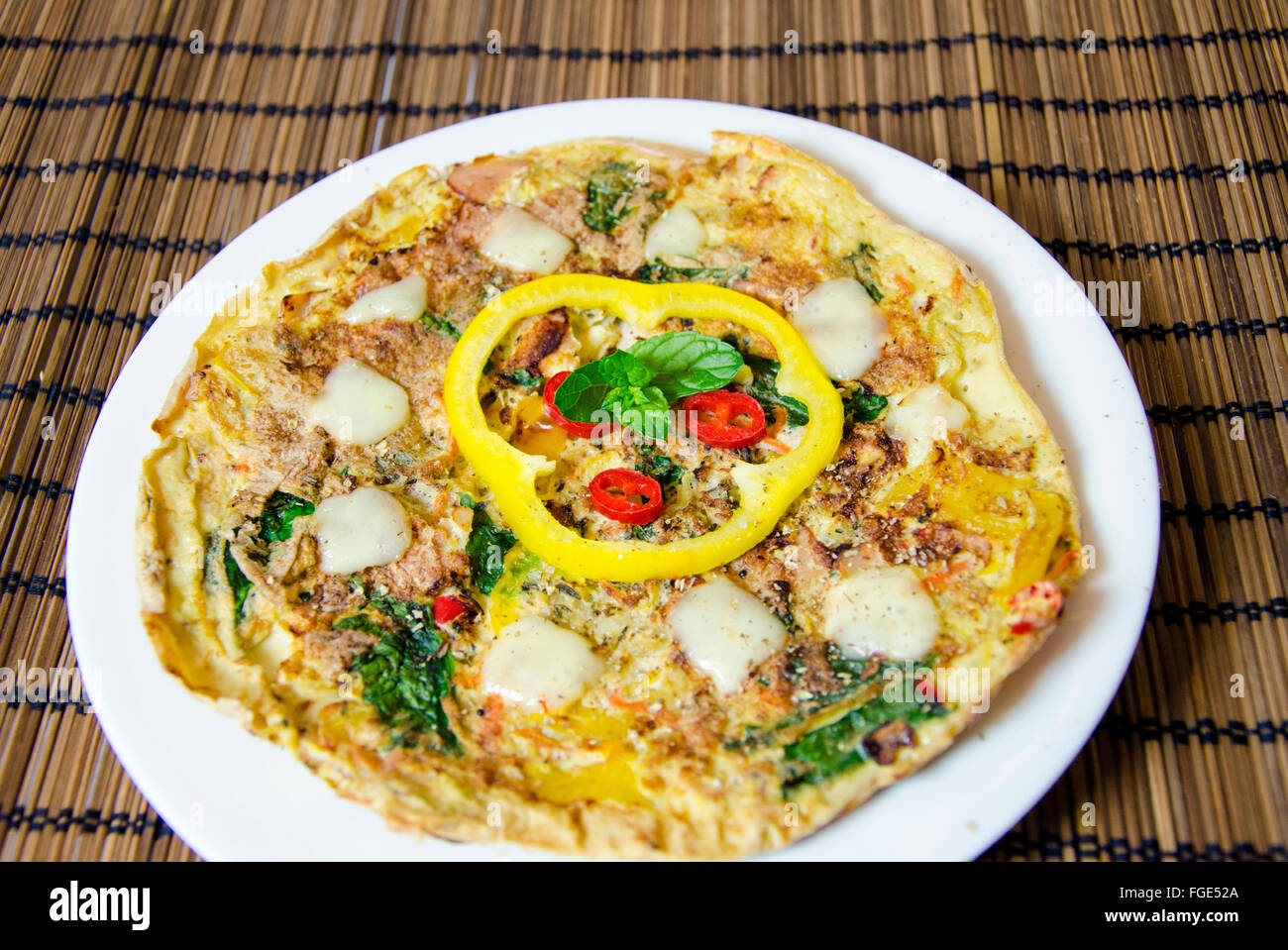 Un spinaci, peperoncino, Menta e Pepe frittata in un piatto sulla tavola di bambù panno. Una dieta sana frittata di farina. Foto Stock
