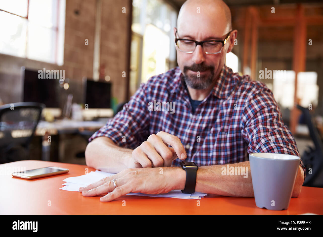 Imprenditore Guardando Smart Watch in ufficio di progettazione Foto Stock