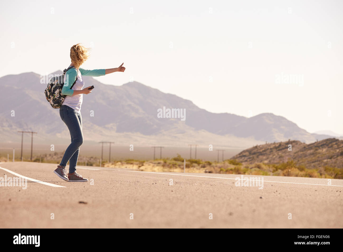 La donna in vacanza autostop lungo la strada di campagna Foto Stock
