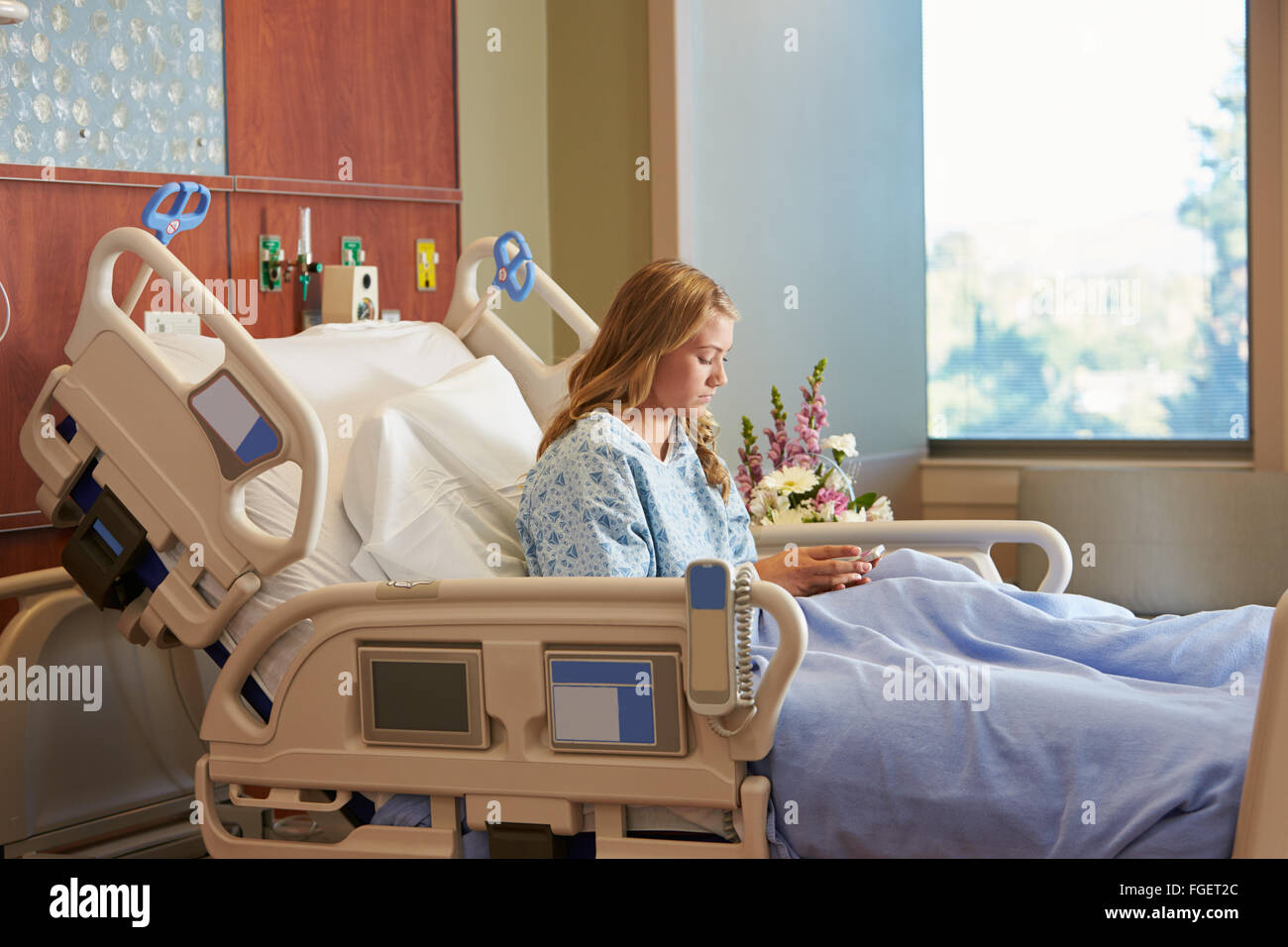 Adolescente paziente femmina nel letto di ospedale tramite cellulare Foto Stock