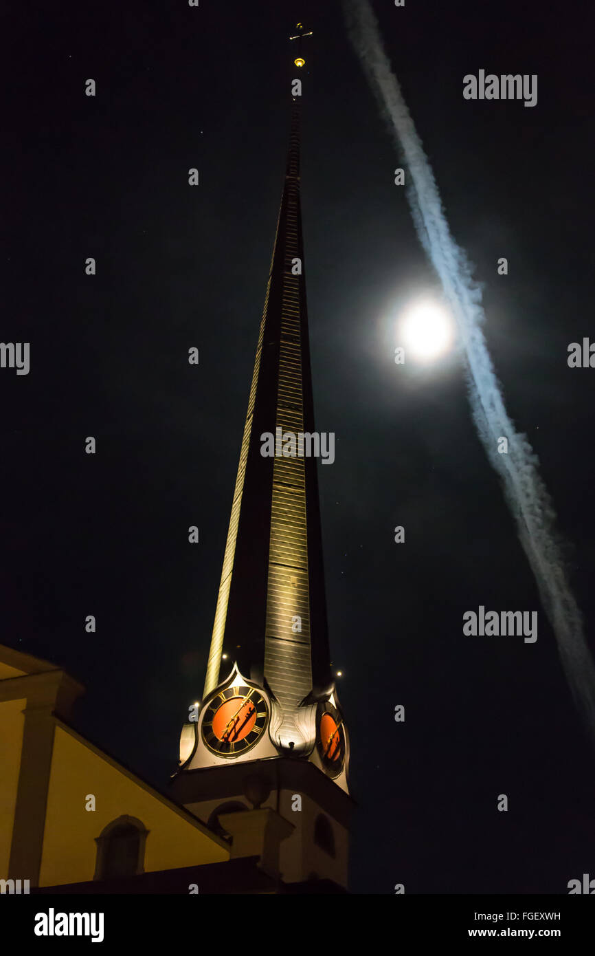 Il campanile della chiesa con la luna e contrails Foto Stock