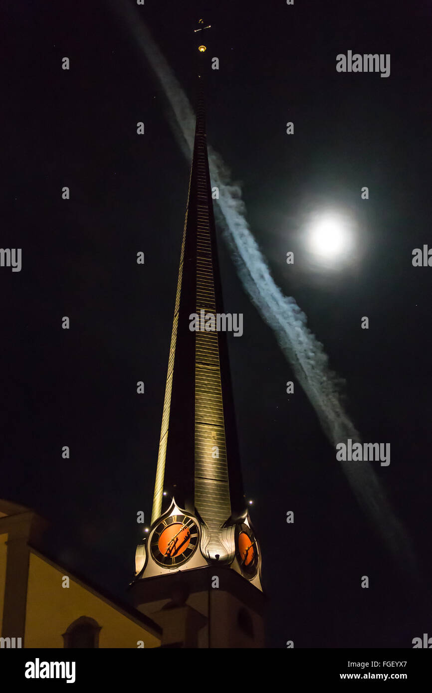 Il campanile della chiesa con la luna e contrails Foto Stock