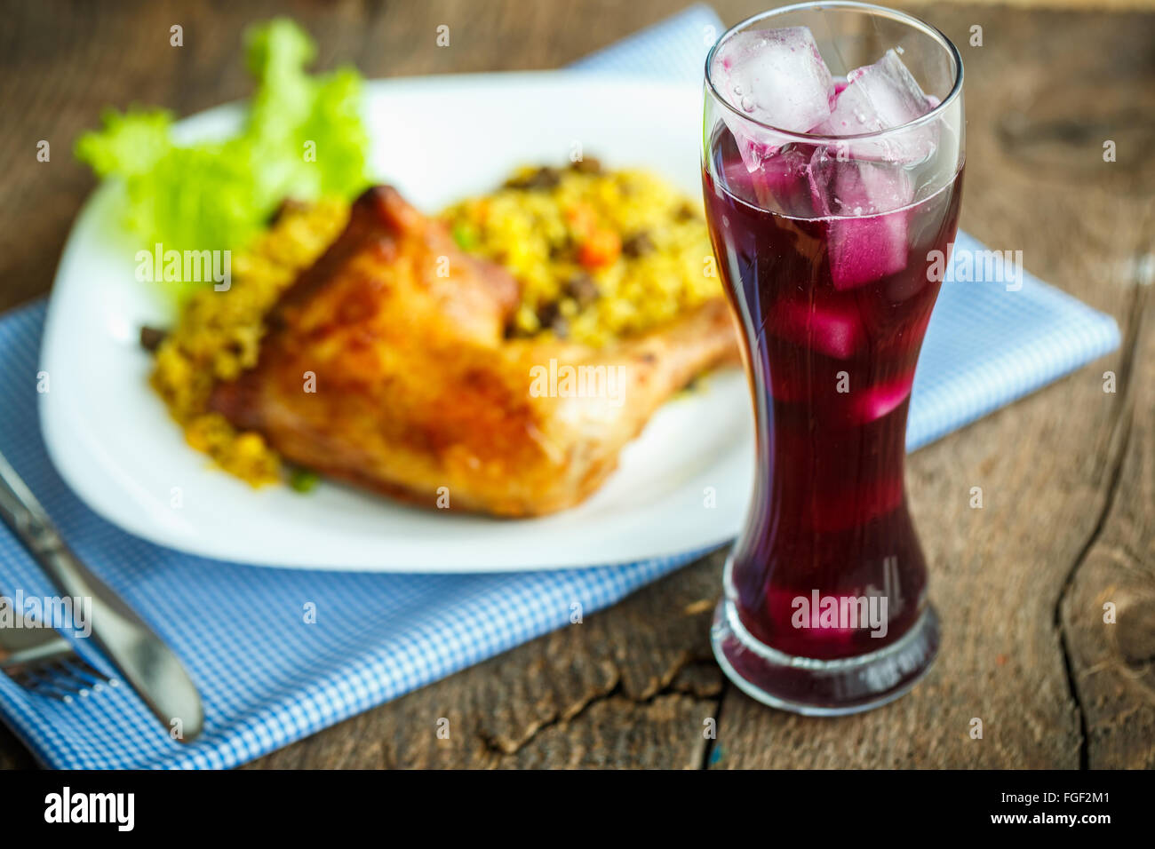 Piatti deliziosi da coscia di pollo con riso e lattuga e un bicchiere di succo di frutta con ghiaccio Foto Stock