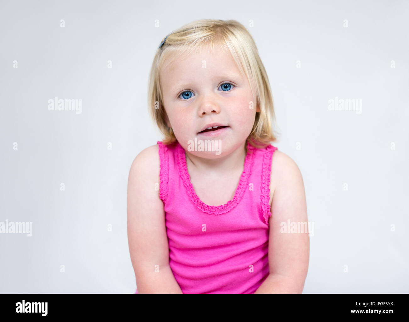 Ritratto di una giovane ragazza con corti capelli biondi e gli occhi blu di indossare un giubbotto rosa sorridente Foto Stock