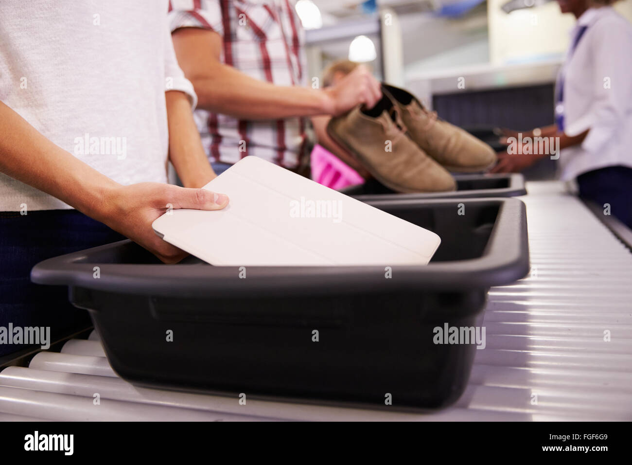 L'uomo mette digitale compressa nel vassoio per il controllo sicurezza in aeroporto Foto Stock