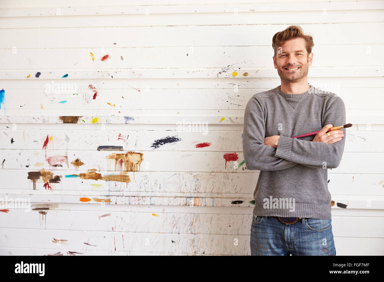Ritratto di Artista maschile appoggiata contro la vernice parete coperta Foto Stock