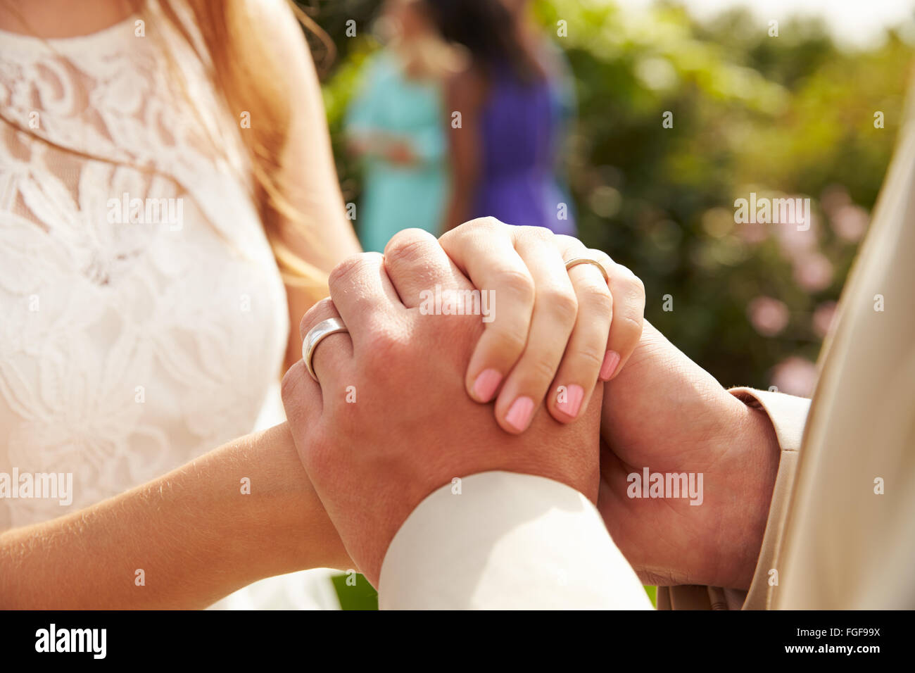 Close up della coppia al matrimonio tenendo le mani Foto Stock