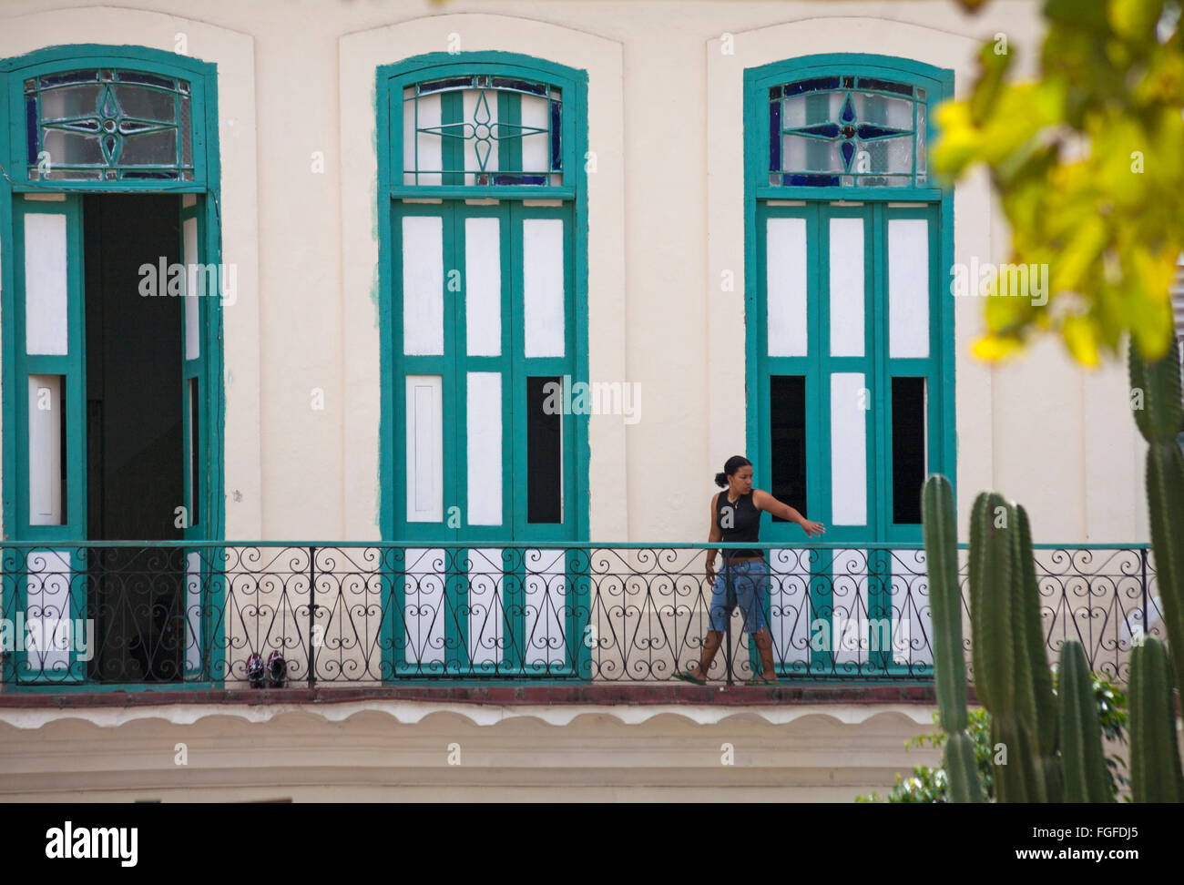 La vita quotidiana a Cuba - donna cubana a piedi lungo balcone a L'Avana, Cuba, West Indies, dei Caraibi e America centrale Foto Stock