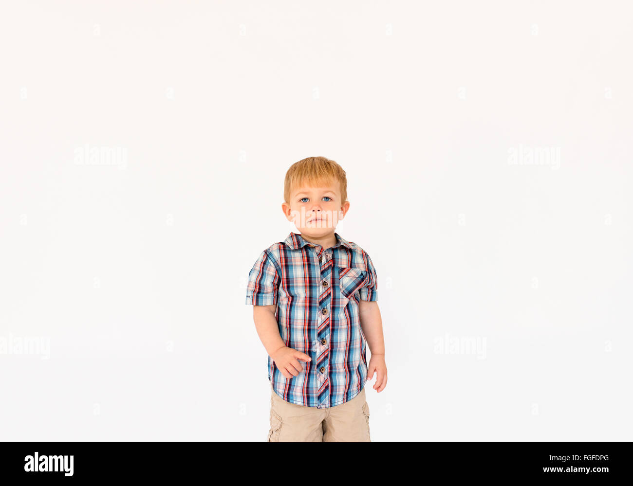 Ragazzo con capelli biondi in piedi contro uno sfondo bianco puntando il dito Foto Stock