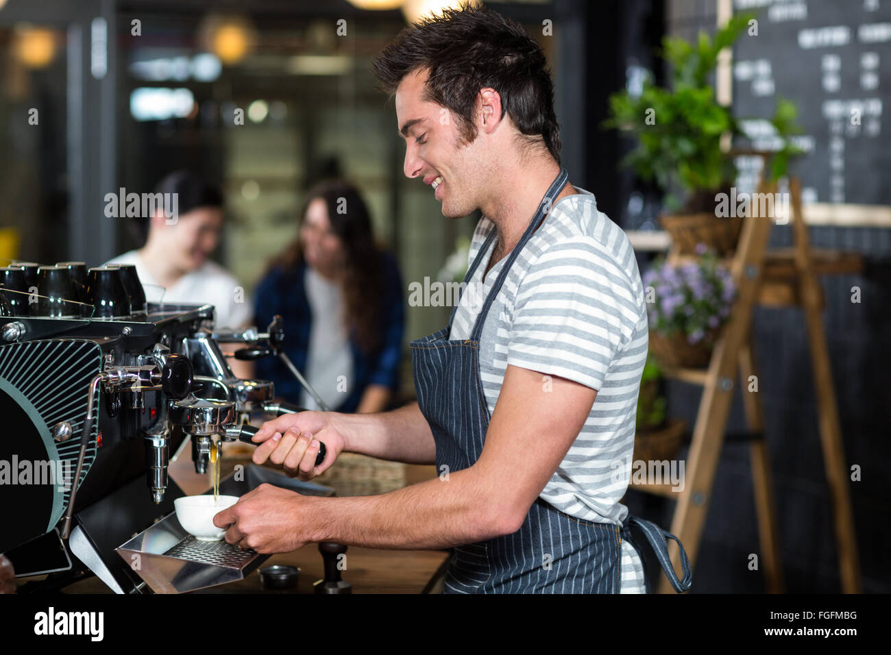 Sorridente barista bollitore per caffè Foto Stock