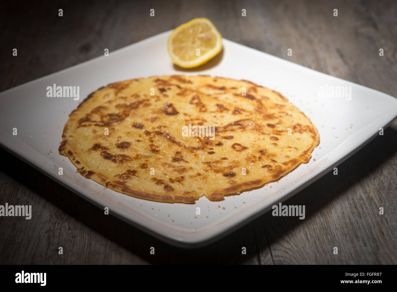 Pancake fatti in casa su una piastra bianca con una fetta di limone fresco e zucchero Foto Stock