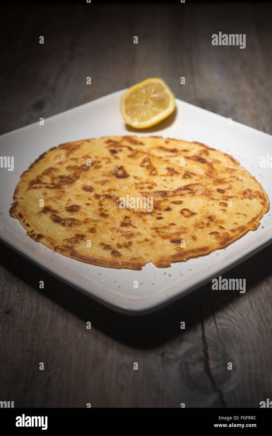 Pancake fatti in casa su una piastra bianca con una fetta di limone fresco e zucchero Foto Stock