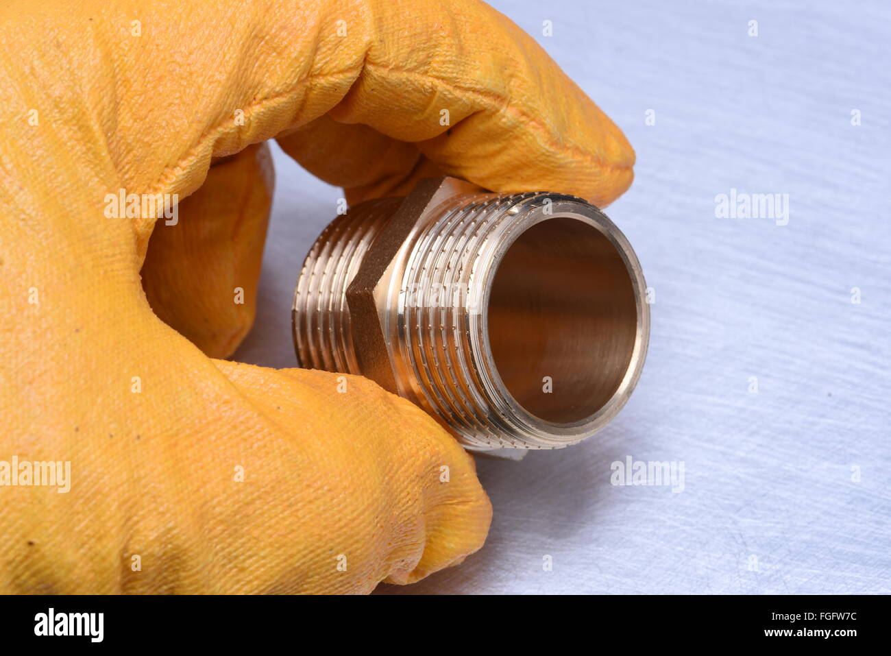 Mano nel guanto trattiene parte idraulica Foto Stock