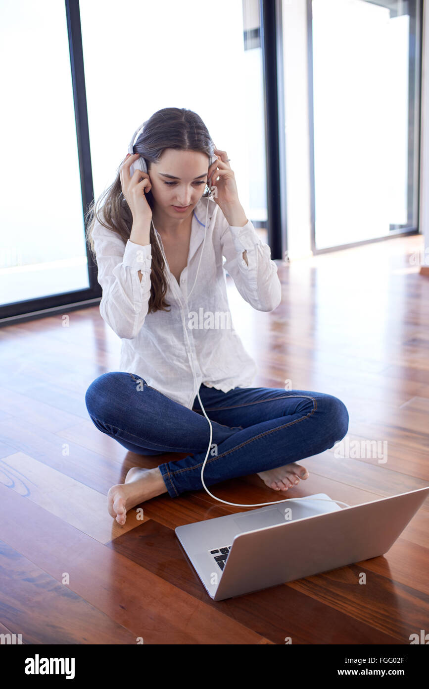 Rilassata giovane donna in casa a lavorare sul computer portatile Foto Stock