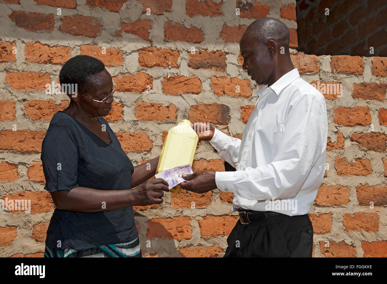 Donna ugandese vendere latte per un prospero cercando il cliente. Foto Stock