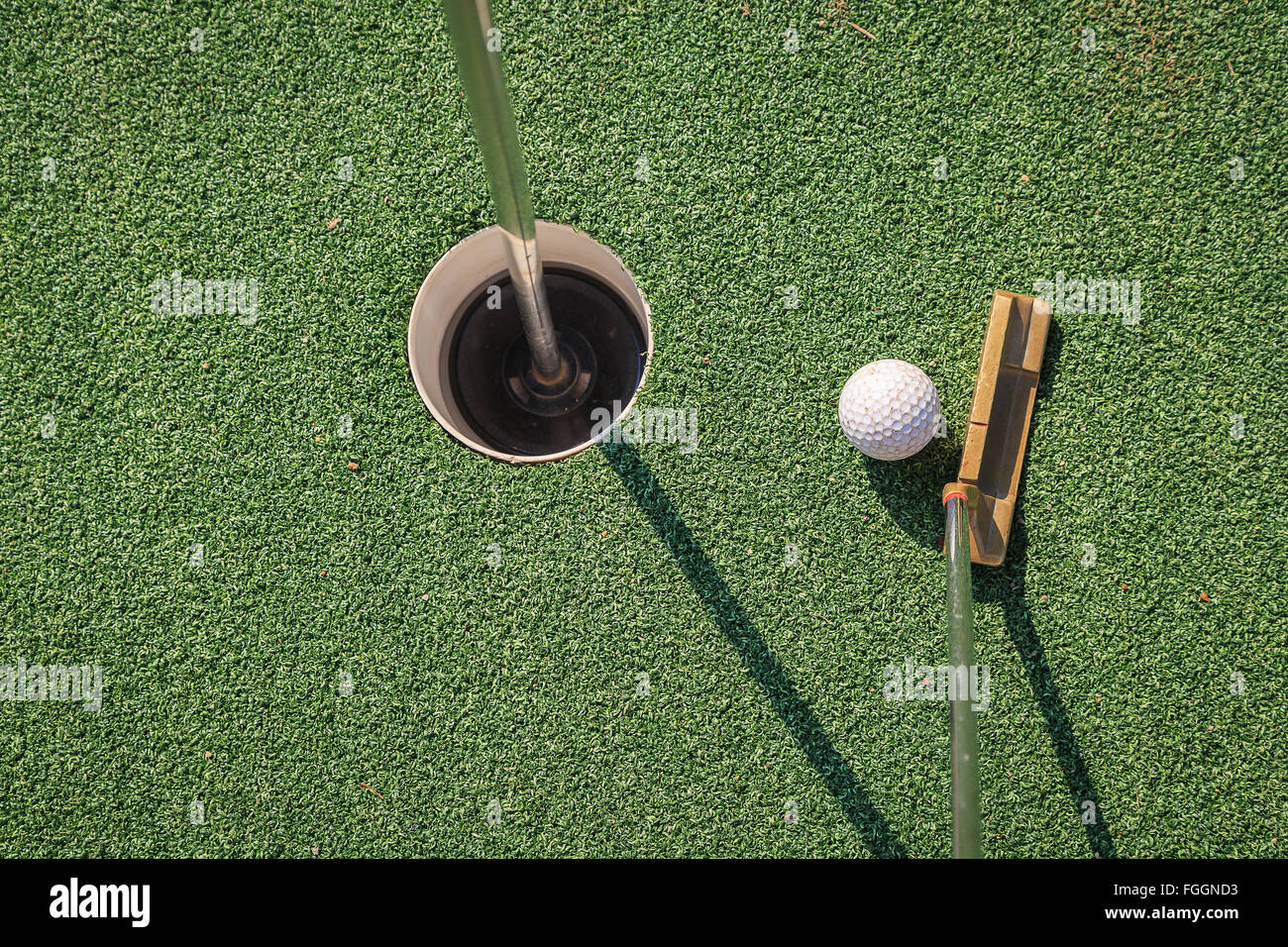 Un vecchio putter messo sul putting green vicino alla pallina da golf per colpire nel foro Foto Stock