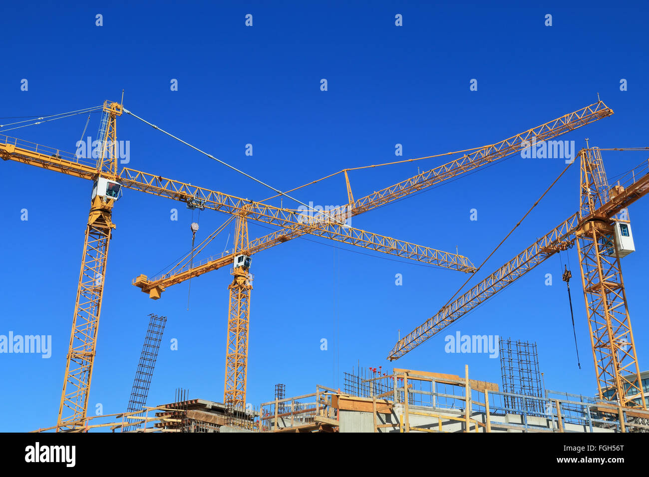 Tre gru per edilizia e costruzione contro il cielo blu. Foto Stock