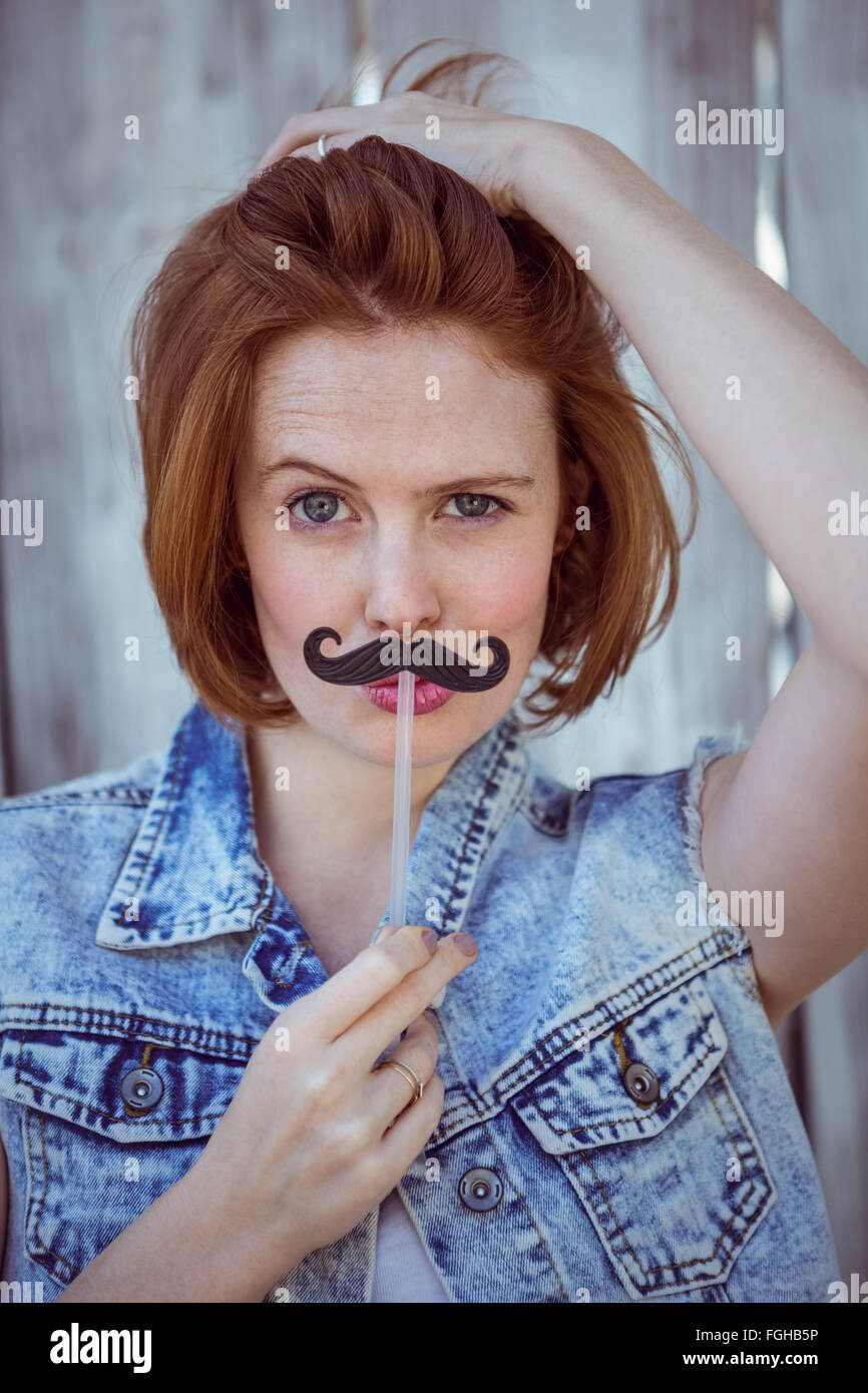 Bella donna parigamba tenendo un baffi finti Foto Stock