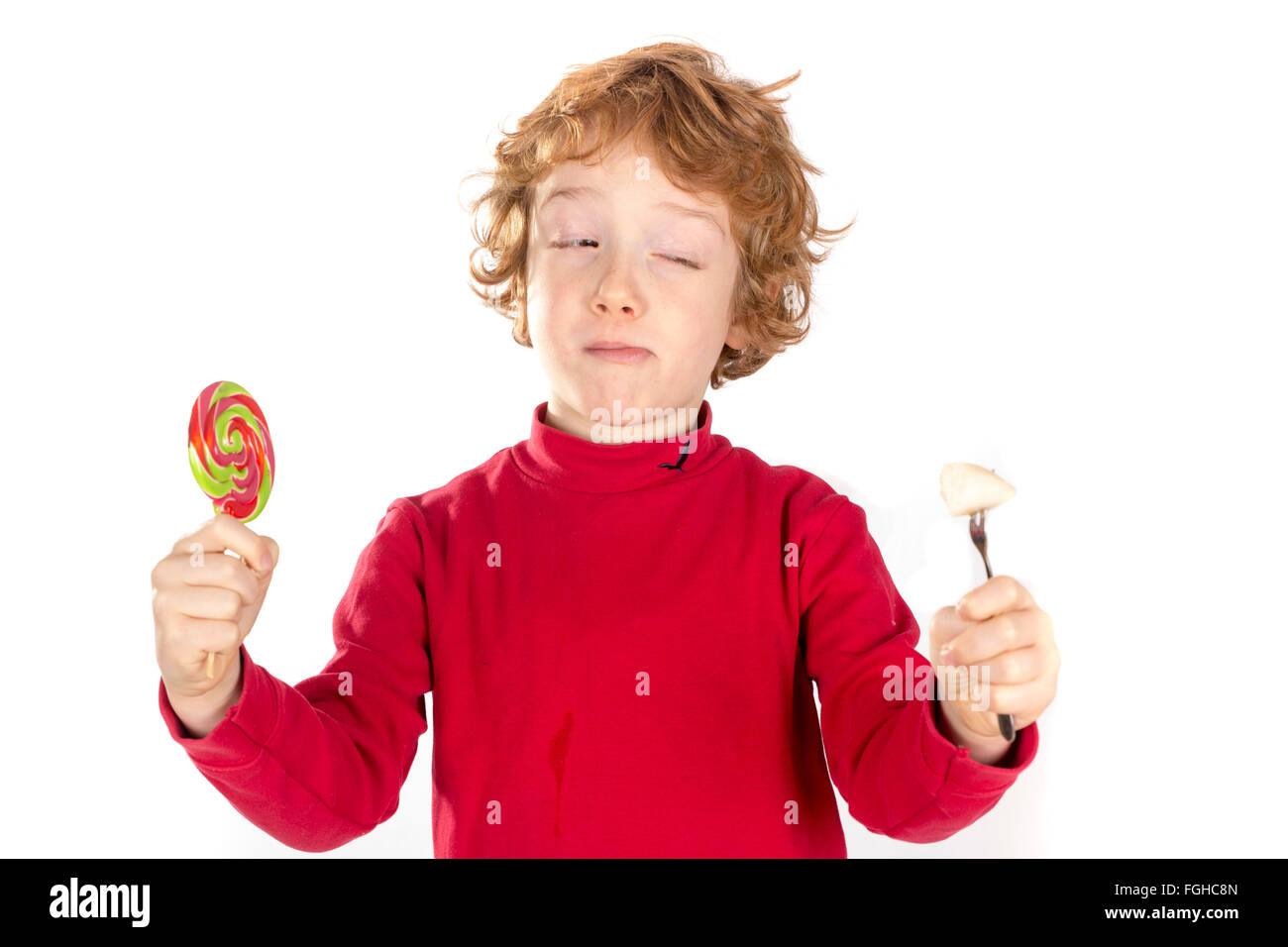 Ragazzo tenendo la caramella di frutta e decidere tra un sano e malsano Foto Stock