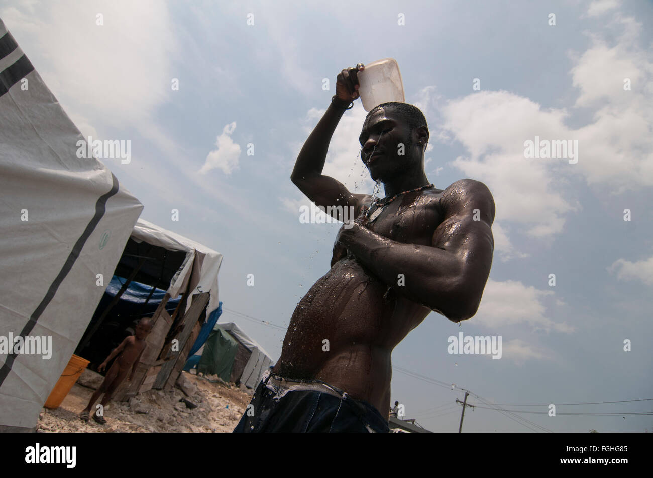 Un uomo lava fino a un campo di fortuna istituito per i superstiti di un terremoto di magnitudine 7.0 che ha colpito Haiti il 12 gennaio 2010 a Port-au-Prince Foto Stock