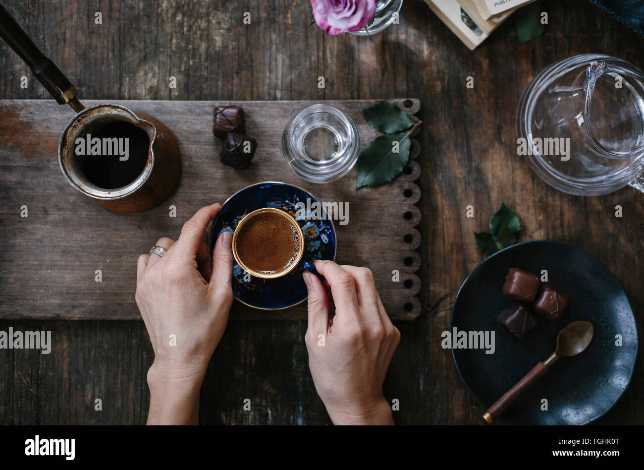 Una donna è in possesso di una tazza di caffè turco con gomma espansa sulla parte superiore (con entrambe le mani) che è servita con acqua e cioccolato. Fotografi Foto Stock