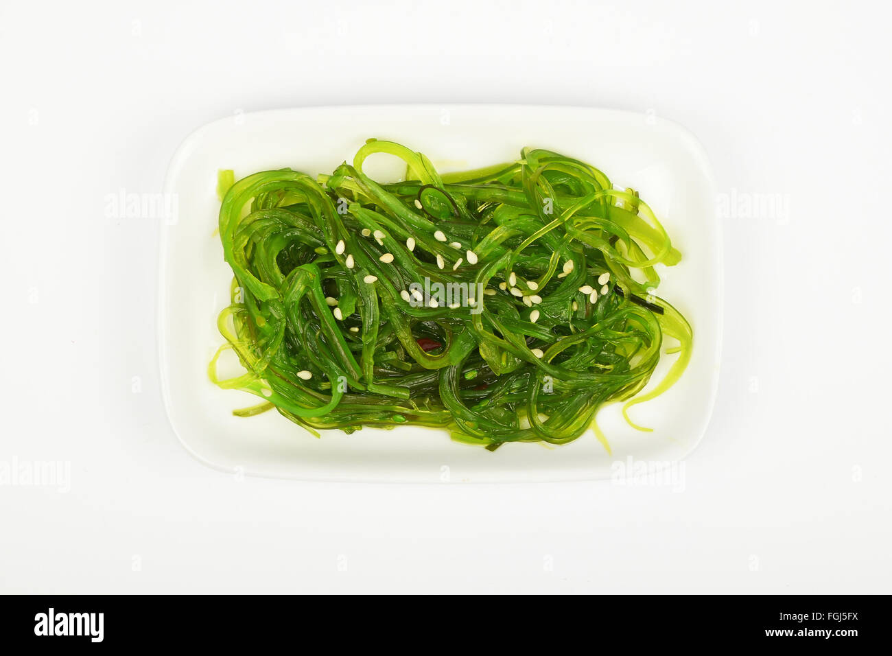Porzione di tradizionali asiatici avidità marinato insalata di alghe marine aperitivo sul piccolo piatto bianco sopra la piastra di sfondo bianca, vista dall'alto Foto Stock