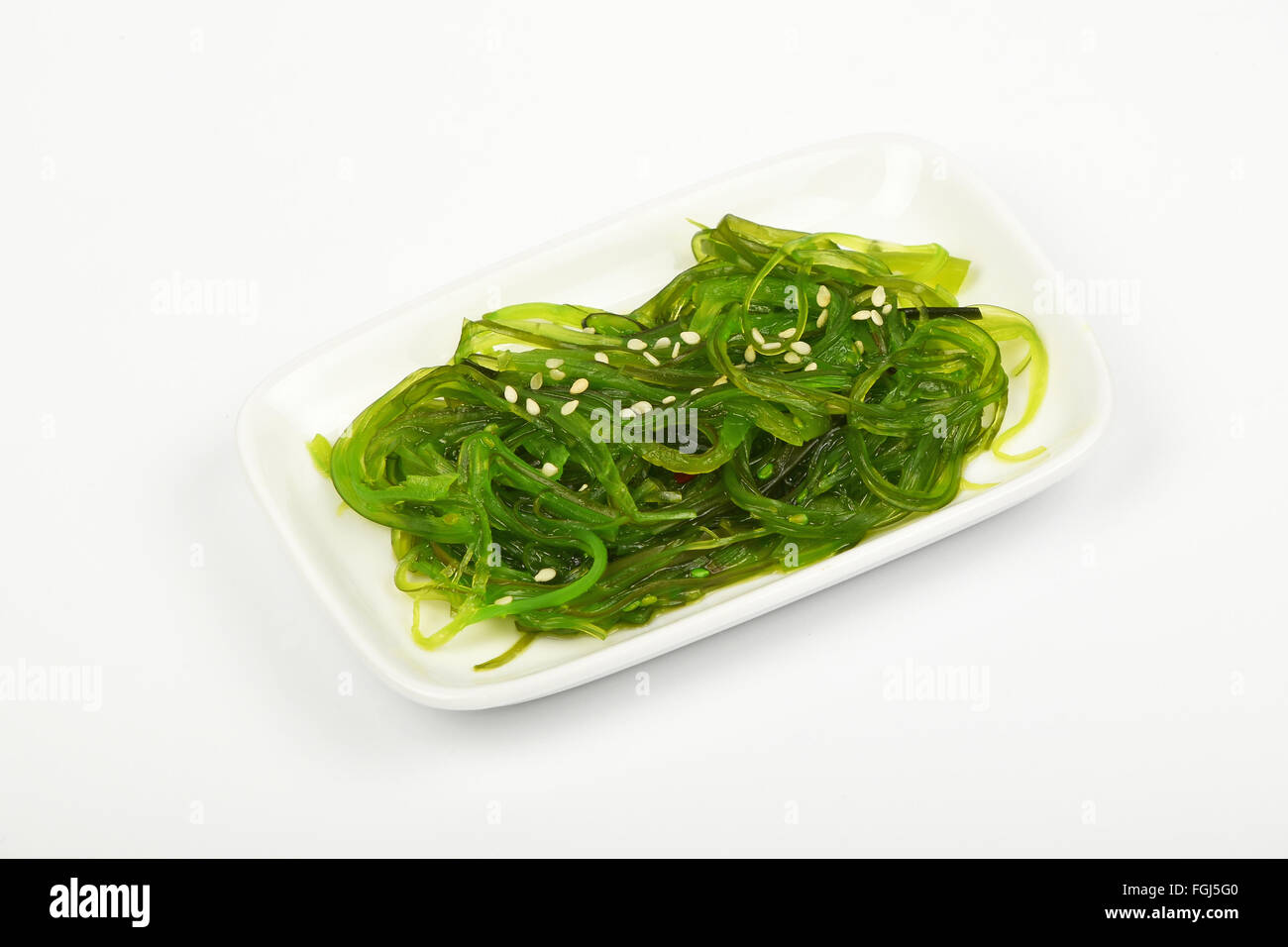 Porzione di tradizionali asiatici avidità marinato insalata di alghe marine aperitivo sul piccolo piatto bianco sopra la piastra di sfondo bianca, angolo alto Foto Stock