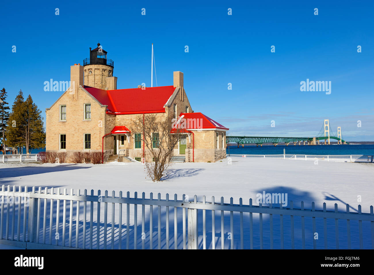 Old Mackinac Point Lighthouse in Mackinaw City si trova in una coltre di neve in Mackinaw City Michigan. Ponte Mackinac è mostrato Foto Stock