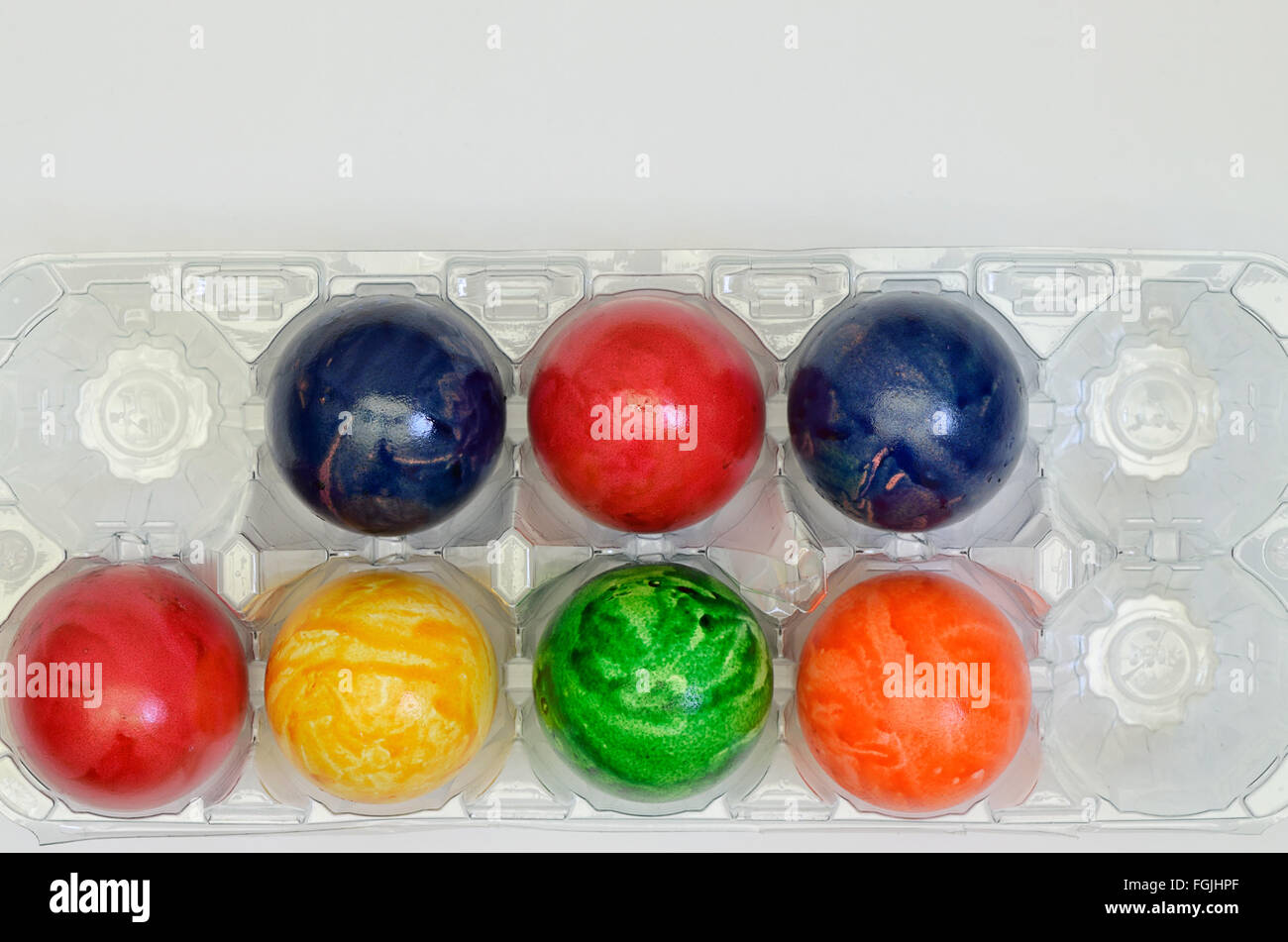 Colorate le uova di pasqua in una scatola di plastica, close up su sfondo bianco, orizzontale Foto Stock