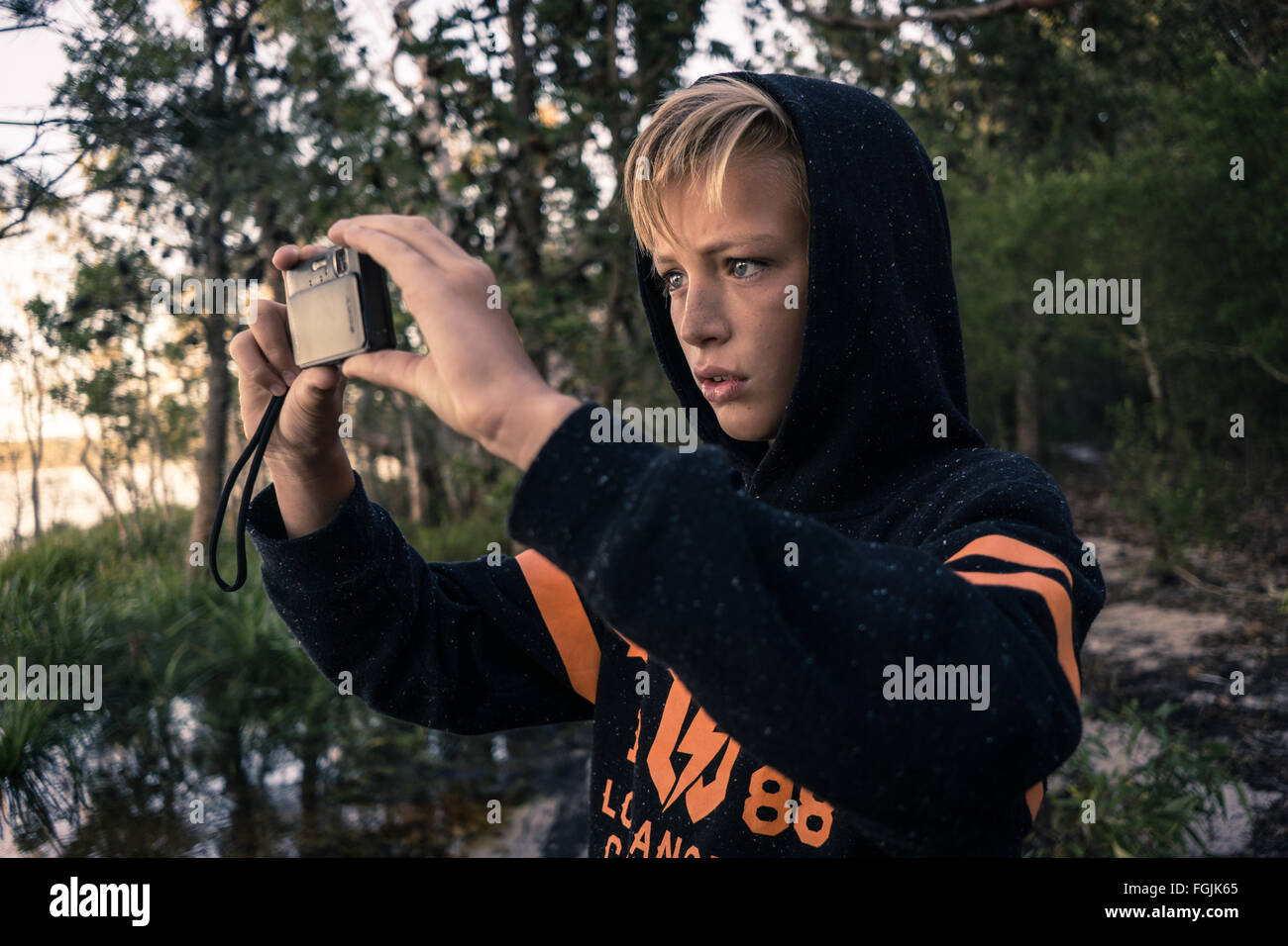 Un ragazzo di scattare una foto mentre in un'avventura nei boschi in riva al lago Foto Stock