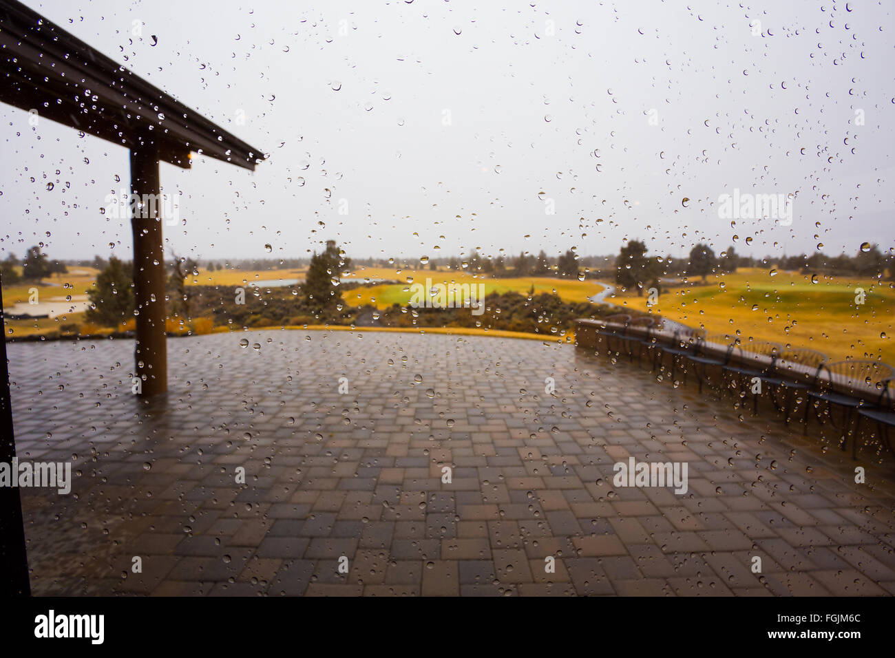 Tempo piovoso a un campo da golf ha lasciato delle gocce di pioggia sulla superficie del vetro con la natura al di fuori in questo riassunto immagine di tessitura. Foto Stock