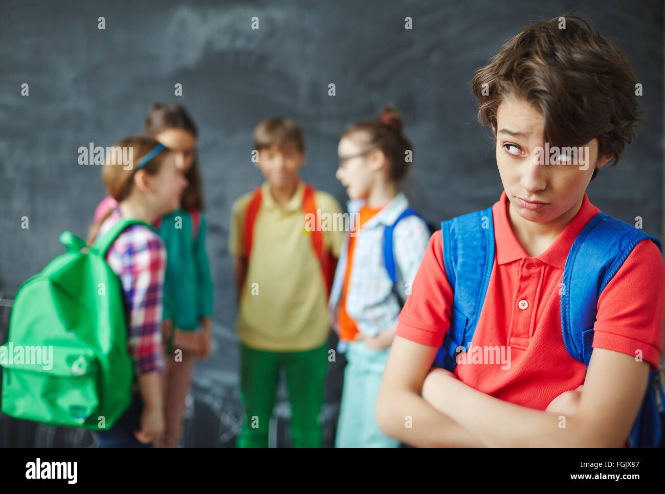 Lonely schoolboy guardando i suoi compagni di classe sullo sfondo Foto Stock