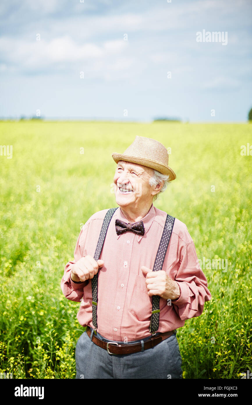 Ben vestito senior man standing in prato sulla giornata di sole Foto Stock