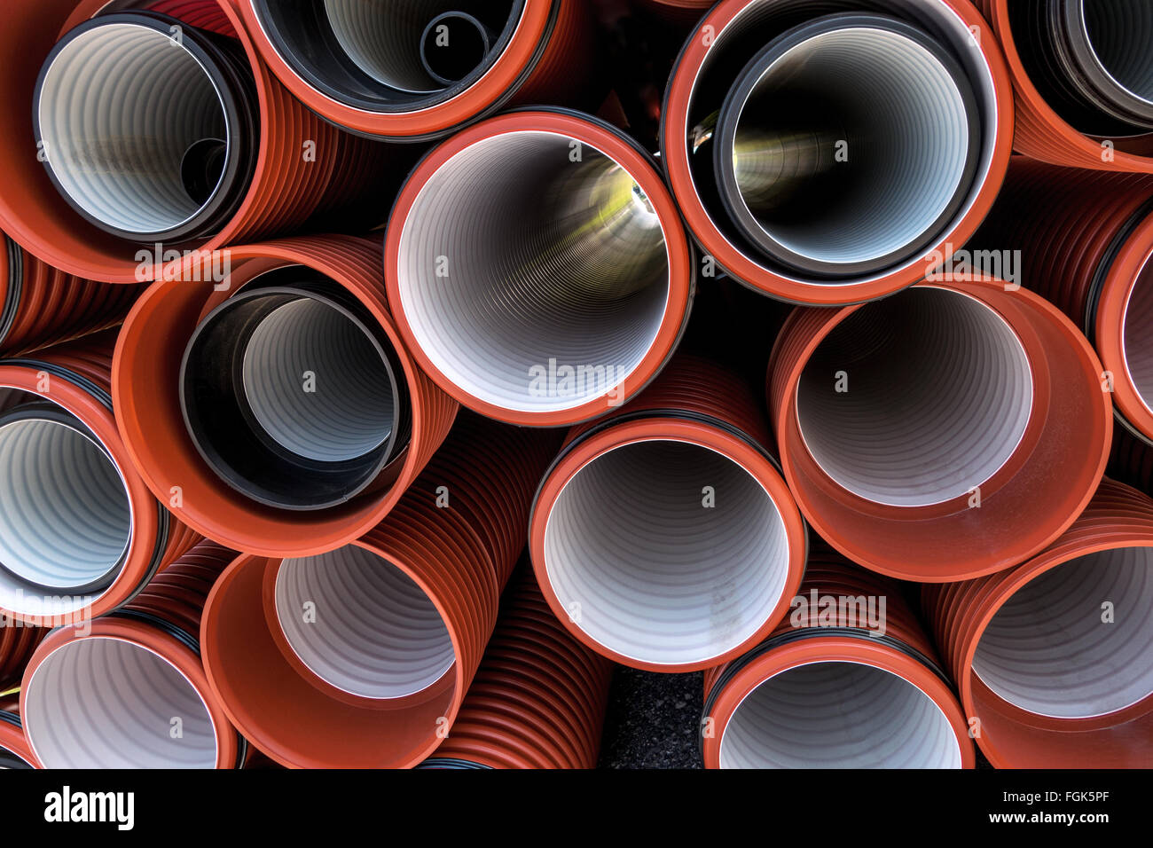 Impilate i tubi in materiale plastico in rosso e nero in diverse dimensioni, alcuni telescopica. La maggior parte delle tubazioni con bianco rivestimento interno. Foto Stock