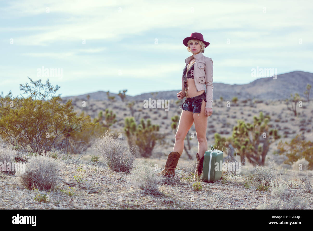 Moda Donna traveler camminando con la valigia e bagagli nel deserto Foto Stock