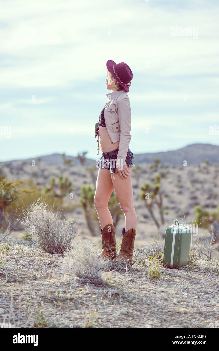 Moda Donna traveler camminando con la valigia e bagagli nel deserto Foto Stock
