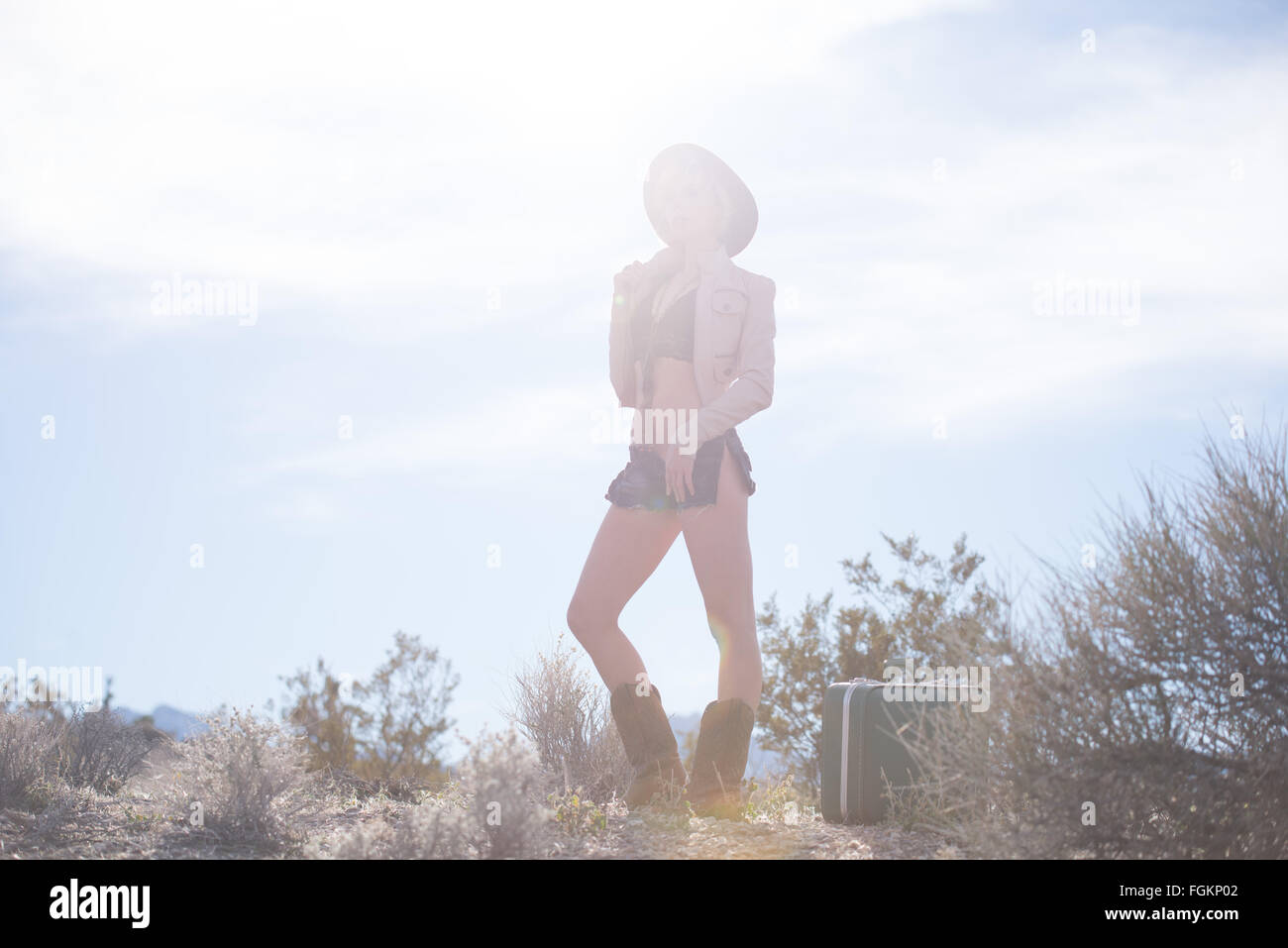 Moda Donna traveler camminando con la valigia e bagagli nel deserto Foto Stock